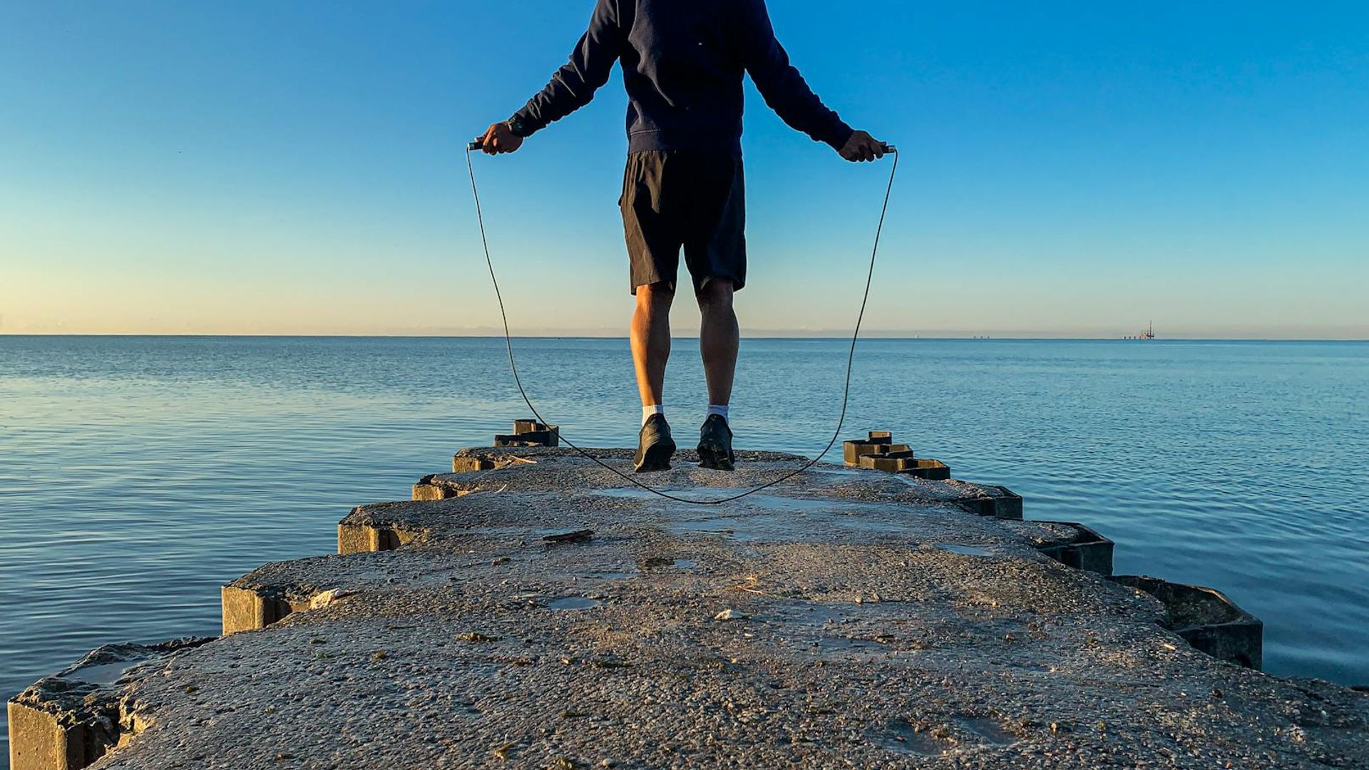 Silhouette of a person in a dynamic cardio pose at sunrise.